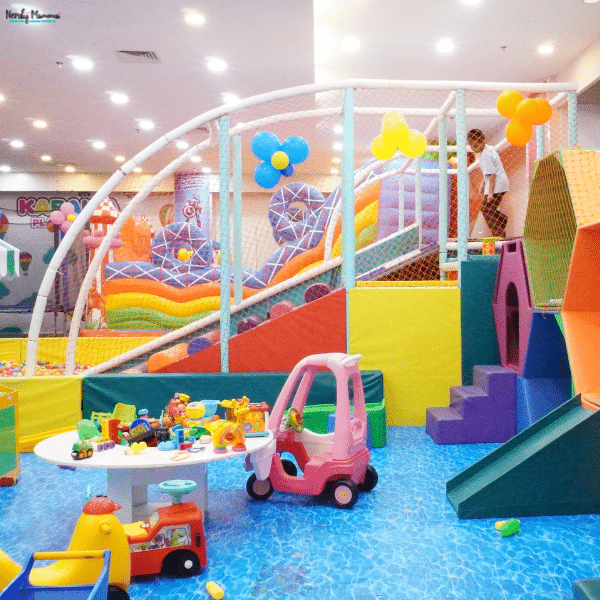 Colorful indoor play area filled with climbing structures, slides, ride-on toys, and activity stations that encourage active play and motor skill development.