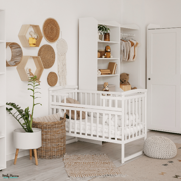 A bright neutral nursery features woven wall decor, wooden hexagon shelves, a white crib, soft rugs, plants, and open storage.