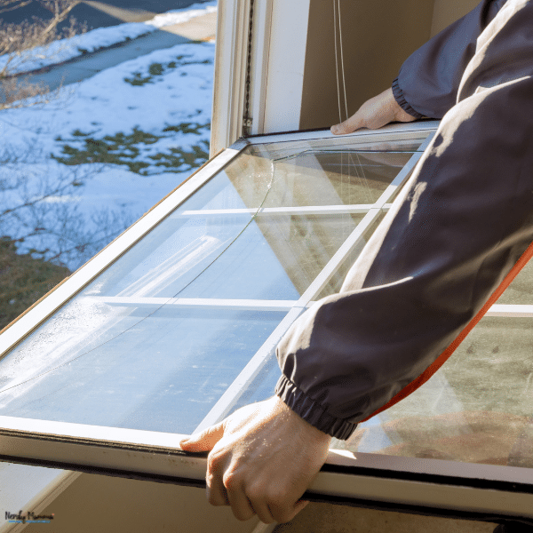 A person holds a large window panel near an opening, showing how a home window can be replaced.