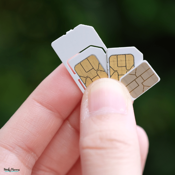 Close-up of several physical SIM cards held between fingers, representing mobile connectivity options for USA travellers.