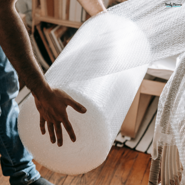 Person handling a large roll of bubble wrap for packing and protecting business products during storage or shipping.
