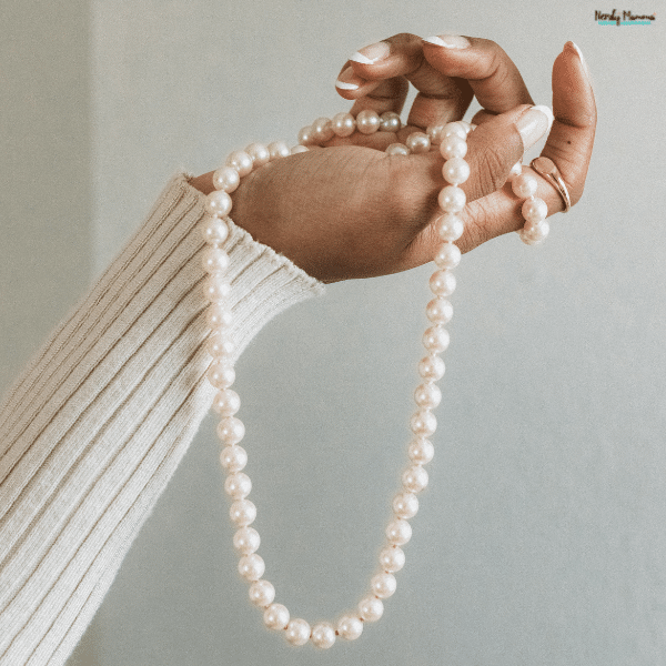 Hands holding a classic strand of white pearls, highlighting a timeless necklace that can become a meaningful heirloom gift for future generations.