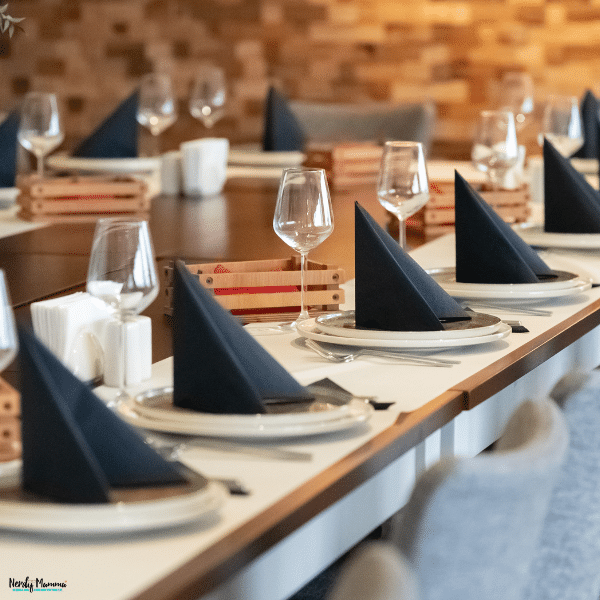 Corporate event venues can feature dining tables set with navy napkins, wine glasses, and layered plates against warm wood-paneled walls.