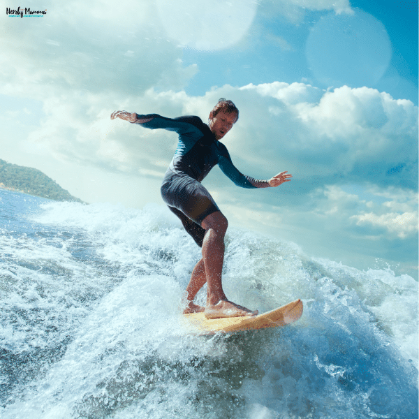 Surfer wearing a blue long-sleeved top rides a yellow board through a foamy wave, illustrating specialized surf equipment in use.