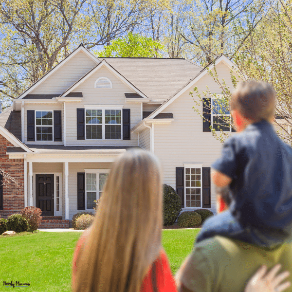 A family views a two-story house with a spacious lawn while considering the right home for their lifestyle.