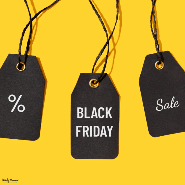 Three dark discount tags hang against a yellow background, illustrating savings compared in In-Store vs. Online Black Friday shopping.